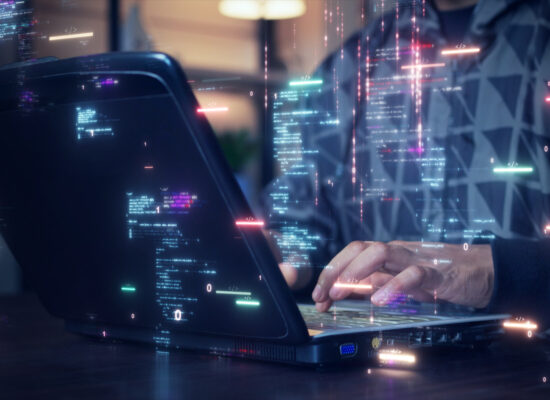 A person types on a laptop in a dimly lit indoor setting, surrounded by colorful digital code overlays. The scene conveys a tech-focused, futuristic mood with a palette of blues and pinks. The individual is partially visible, wearing a geometric-patterned hoodie, and the focus is on the hands and laptop screen.